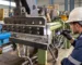 Technician inspecting the head of a used cold-feed rubber extruder