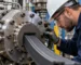 Technician inspecting die alignment on a rubber extruder machine